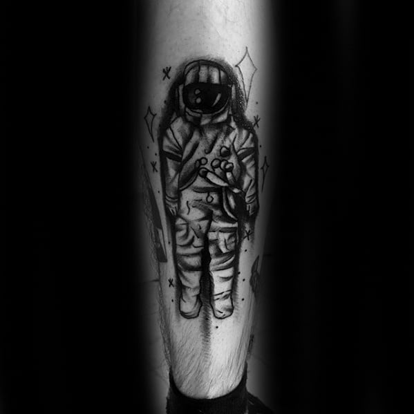 Blackwork Deja Entendu astronaut tattoo with bold lines, star details, and a dark, shadowy space theme on the lower leg.