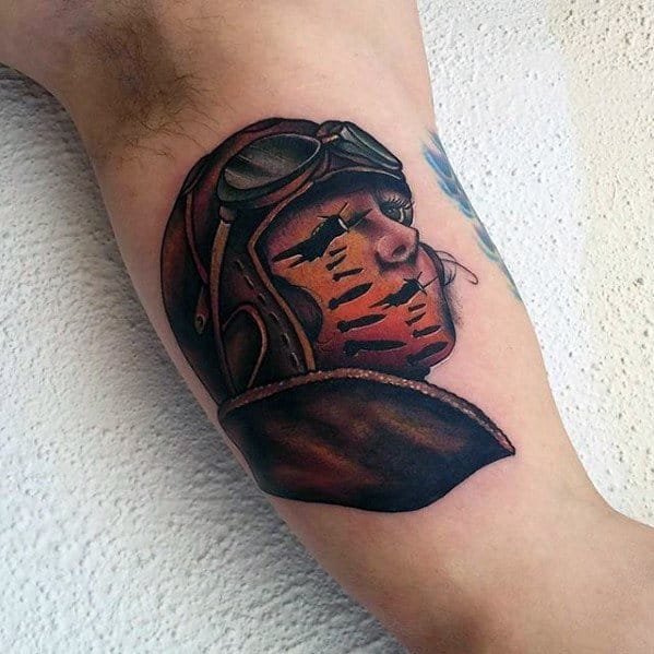 Colorful tattoo of a vintage pilot’s profile with a sunset landscape and flying planes blended into the face, symbolizing adventure and freedom.
