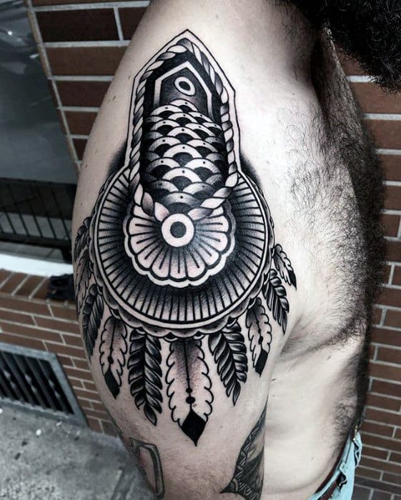 Ornate epaulette tattoo with bold geometric patterns, fan-like centerpiece, and feathered tassels flowing over the upper arm.