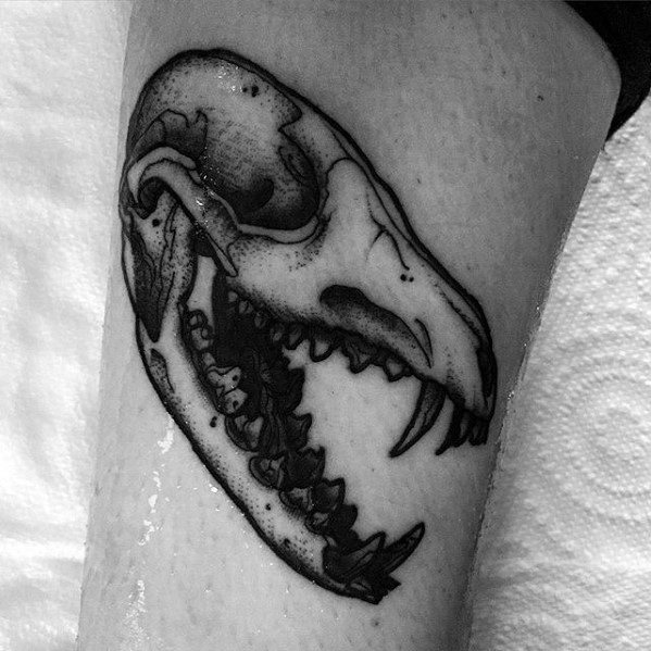 Black and grey tattoo of a fox skull with bold outlines and sharp shading, placed on the arm for a clean anatomical look.