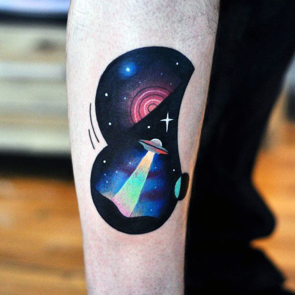 Colorful space-themed tattoo of a UFO beaming light in a cosmic scene, set within a bold black abstract shape with stars and planets.