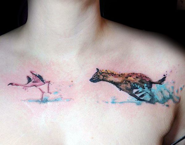 Watercolor-style chest tattoo of a hyena chasing a flamingo, using vibrant splashes of pink, blue, and brown to create motion and whimsy.