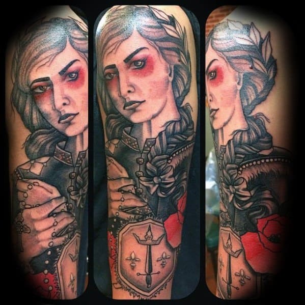 Bold Joan of Arc tattoo sleeve with red accents, braided hair, armor, sword, and shield featuring a cross, blending realism and neo-traditional style.
