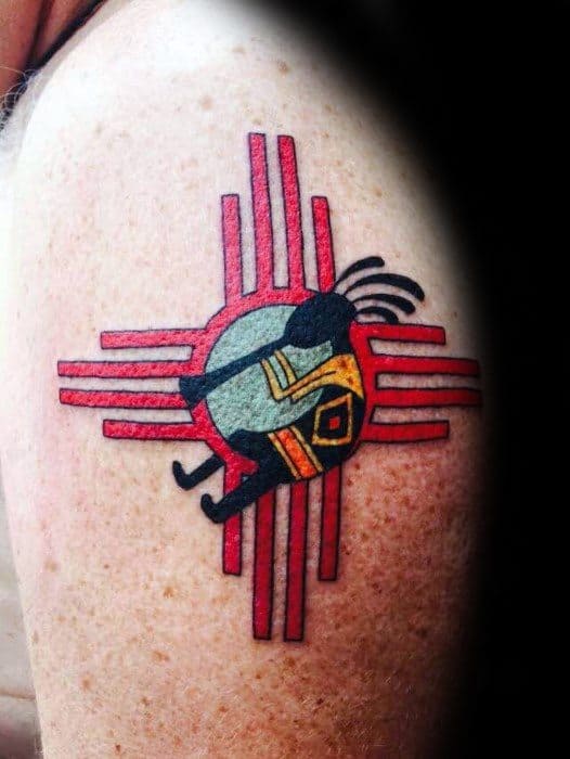Kokopelli tattoo set against a bold red and black Southwestern design, featuring a sun symbol and tribal patterns inspired by Native American art.