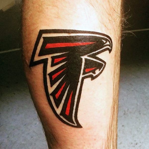 Bold Atlanta Falcons logo tattoo on the calf, featuring sharp black outlines and vivid red accents in a dynamic falcon design.