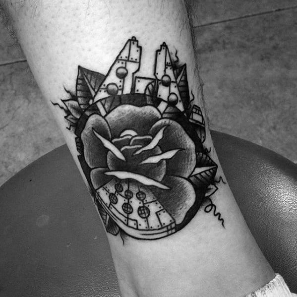 Black and grey Millennium Falcon tattoo fused with a rose and geometric cityscape, combining sci-fi and floral elements.