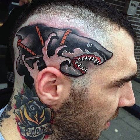 Neo-traditional shark tattoo on the scalp with red rope details, open jaws, and bold black and pink shading for a striking effect.