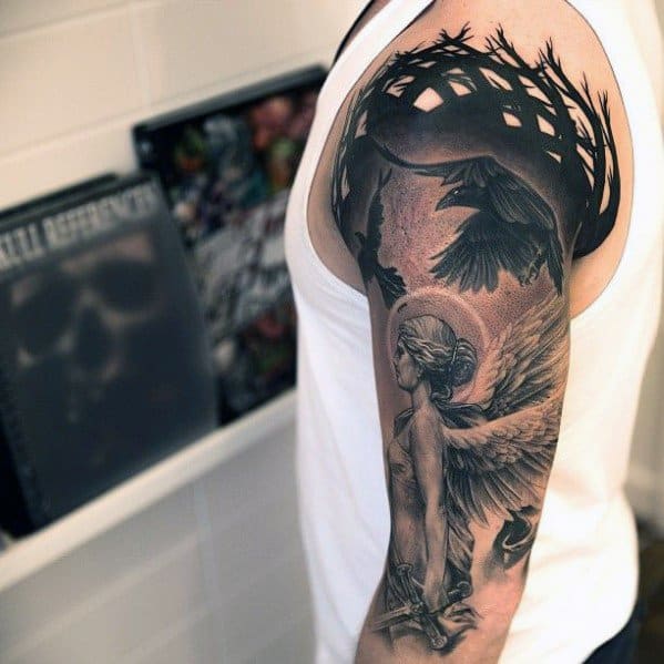 Realistic black and grey sleeve tattoo featuring an angelic figure, ravens in flight, and a thorned crown motif around the shoulder.