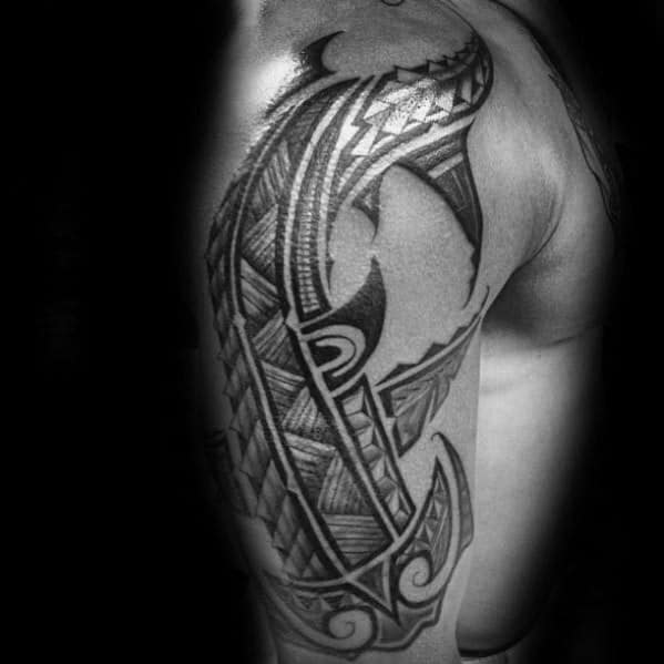 Polynesian shark tattoo on shoulder and upper arm with bold tribal patterns symbolizing resilience, strength, and connection to the ocean.