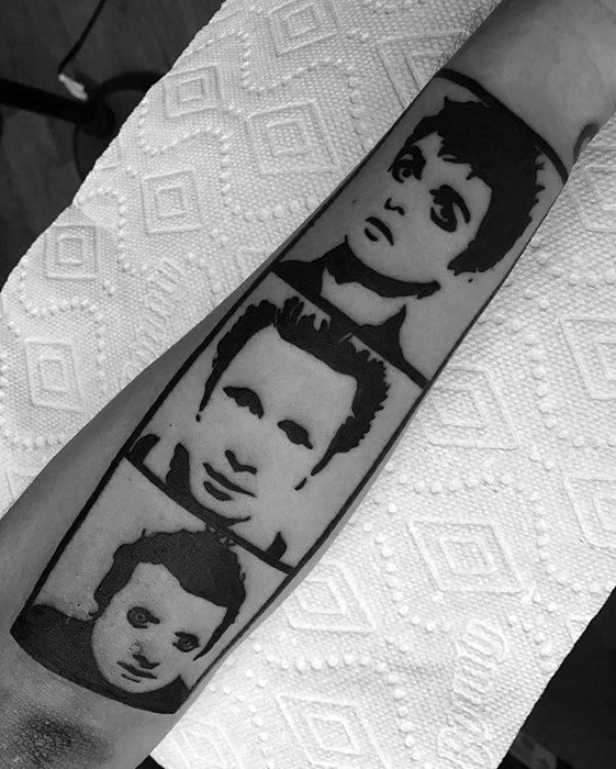 Black forearm tattoo of stencil-style portraits of Green Day’s band members: Billie Joe Armstrong, Mike Dirnt, and Tré Cool.