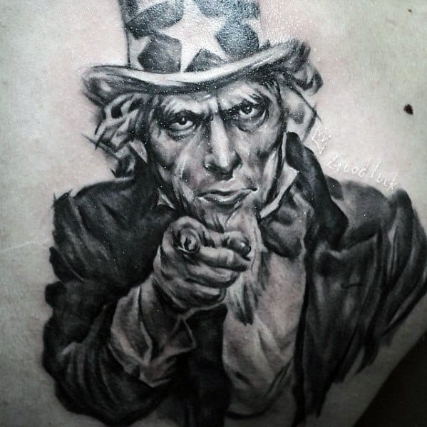 Realistic Uncle Sam tattoo in black and gray with detailed facial expression, pointing forward and the words “Good Luck” subtly inked.