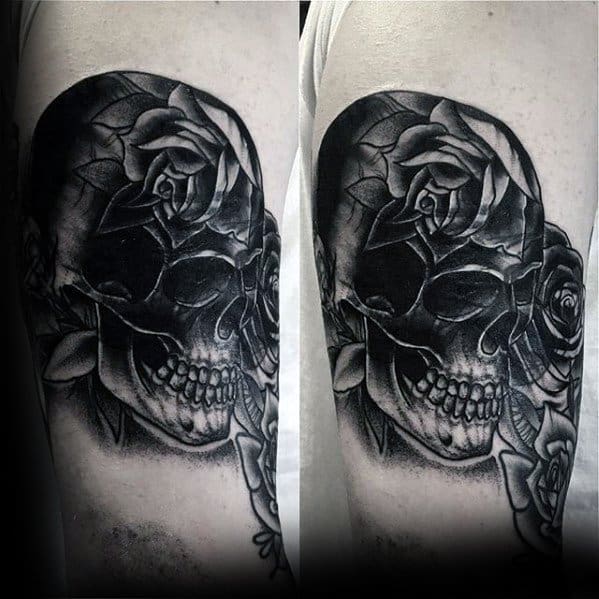 Blast over black and gray skull tattoo with roses on an upper arm