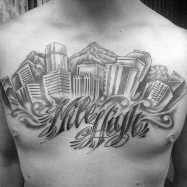 Black and grey chest tattoo of the Denver skyline with mountains and bold script reading "Mile High" beneath swirling clouds.