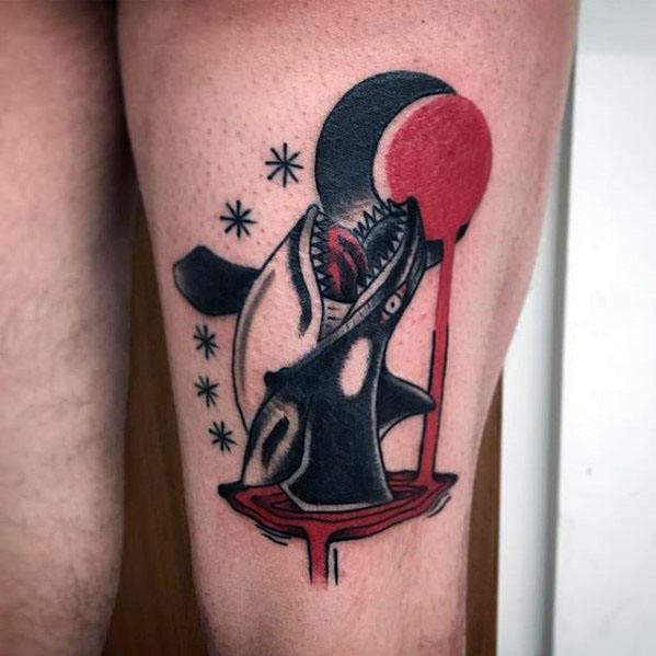 Bold black and red orca tattoo on the thigh, featuring the whale with its mouth open, surrounded by a dripping red circle and scattered stars for a dramatic and modern design.