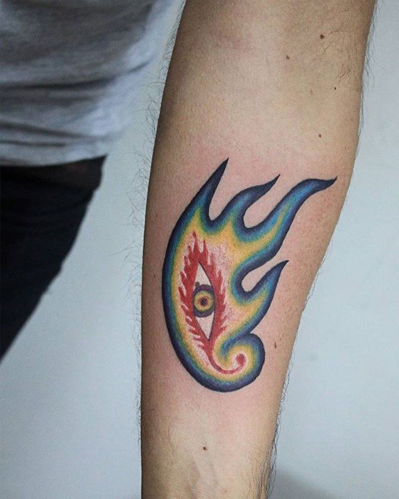 Colorful Tool-inspired forearm tattoo of a flaming eye with rainbow hues and sharp edges, resembling the band’s iconic logo.
