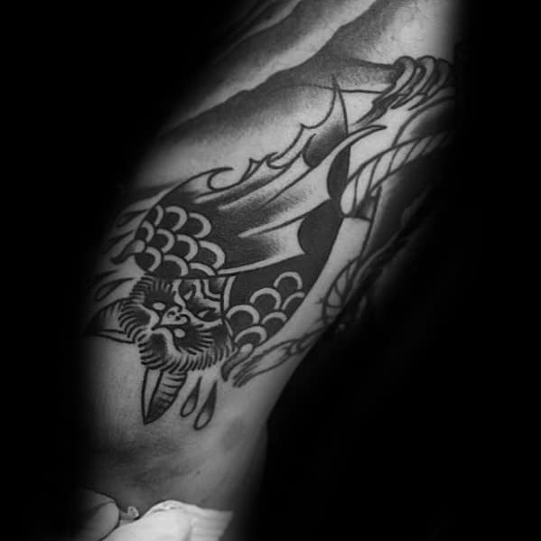 Black and grey traditional bat tattoo hanging upside down with teardrop details and bold scales on the wings and body.