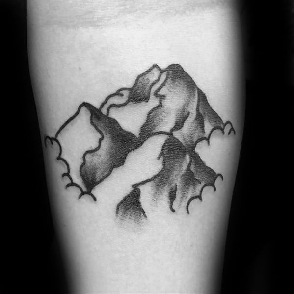 Minimal black and grey mountain tattoo with soft shading and curved cloud outlines wrapping around the peaks.