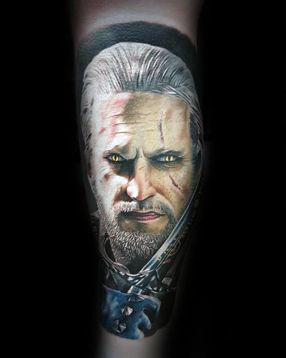 Ultra-realistic Witcher tattoo of Geralt’s face with glowing yellow eyes, facial scars, and detailed armor on the forearm.