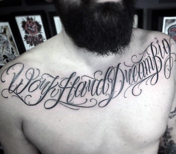Chest tattoo in flowing cursive script that reads “Work Hard Dream Big,” stretching across the collarbone from shoulder to shoulder.