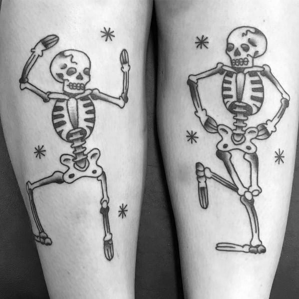 Matching dancing skeleton tattoos on both legs, featuring playful poses and star accents, creating a fun and lively design.