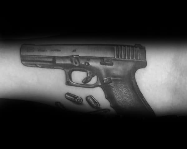 Realistic black and grey tattoo of a Glock pistol on the forearm, featuring detailed shading with bullets falling below for a bold and dynamic effect.