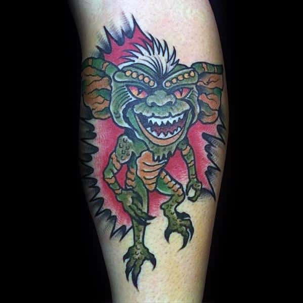 Gremlin tattoo with red eyes, sharp teeth, and a dynamic pose, bursting through the skin with bold outlines and vibrant colors.