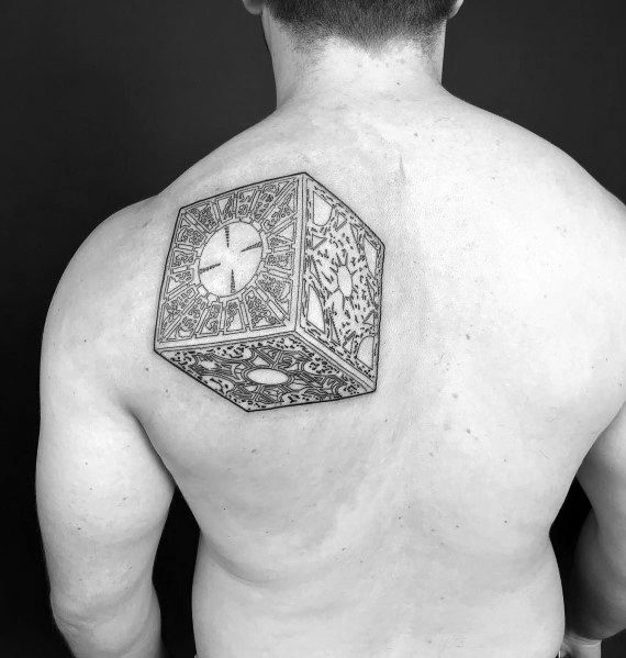 Black and grey *Hellraiser* tattoo of the Lament Configuration puzzle box on the upper back, featuring intricate linework and detailed patterns.