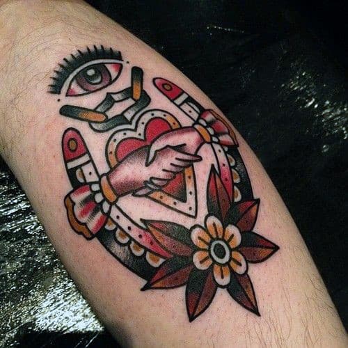 Traditional tattoo of clasped hands with heart, eye, and flower on the inner forearm