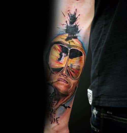 Realistic Hunter S. Thompson tattoo featuring aviator glasses reflecting a desert scene, a surreal melting face, and an explosive bat silhouette.