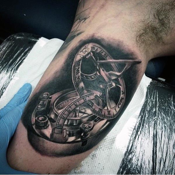 Black and grey tattoo of a detailed sundial and compass, featuring realistic shading, Roman numerals, and intricate metallic elements