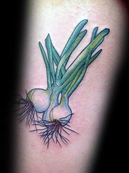 Colorful green onion tattoo on the forearm, featuring vibrant green stalks, white bulbs, and detailed roots for a realistic botanical design.