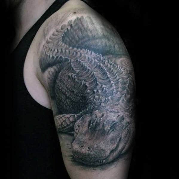 Detailed alligator tattoo on a person's upper arm featuring intricate scales and realistic shading