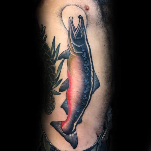 Realistic salmon tattoo with vibrant red and blue tones, leaping toward a glowing moon, creating a striking and dynamic ribcage design.