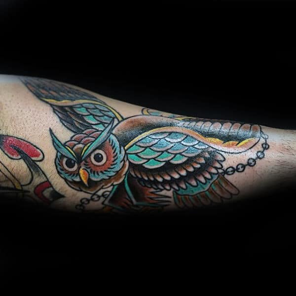Male With Tattoo Of Owl And Chain Traditional Design On Outer Forearm