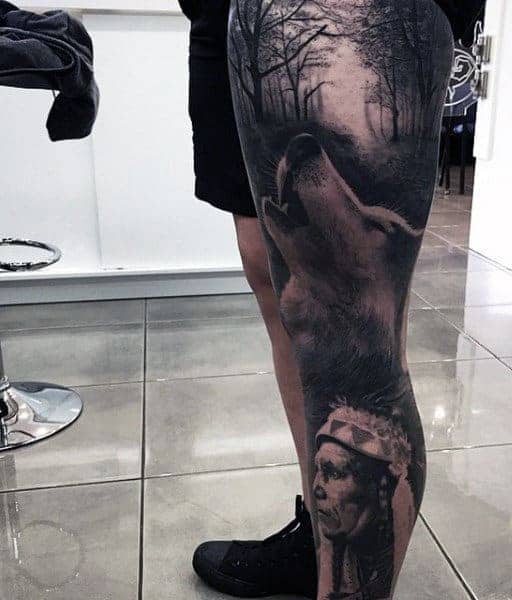 Leg tattoo featuring a wolf howling in a forest with a portrait below