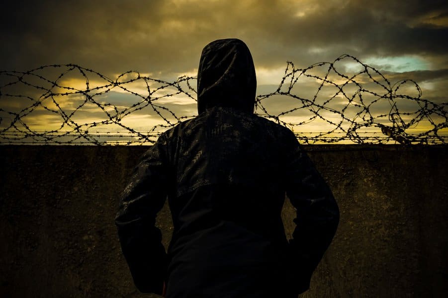 man at the prison wall with barbed wire