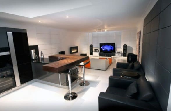 Modern living room with sleek black and white design, featuring a TV, sound system, minimalist furniture, and a chic bar