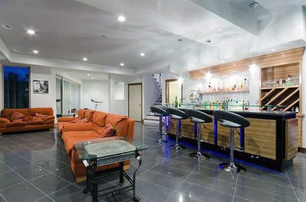 Spacious modern basement with a sleek bar, orange sectional sofa, and glossy tile flooring