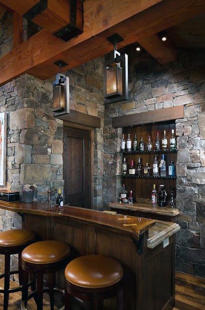 Cozy bar with stone walls, wooden stools, and shelves of assorted liquor bottles