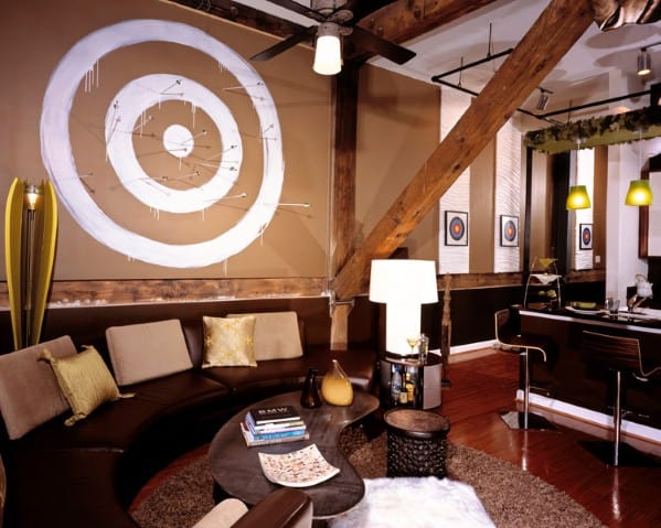 Trendy loft with a target wall design, round sofa, modern decor, and exposed wooden beams
