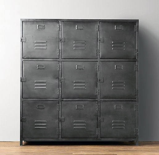 A set of nine metal lockers in three rows on a wooden floor against a gray wall