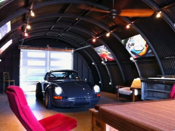 A vintage car rests inside a sleek garage adorned with curved walls and vibrant artwork