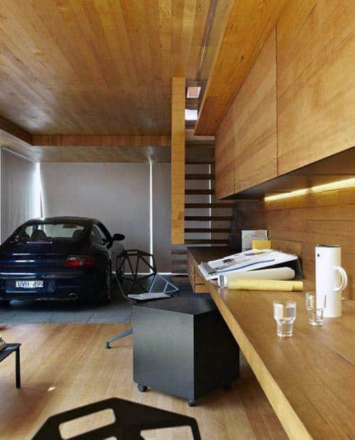 Modern wooden office with a garage theme, featuring a parked car, desk, papers, and car-themed decor