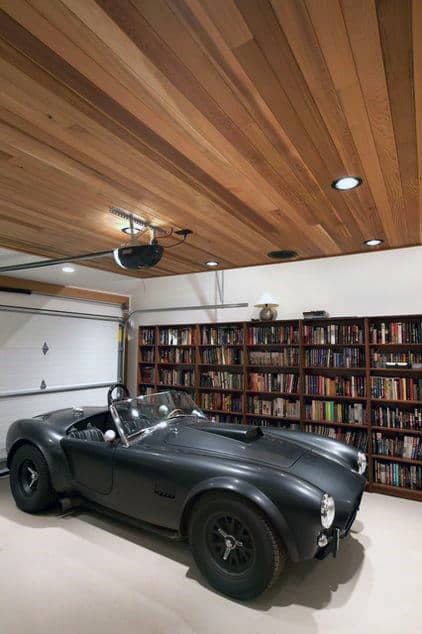 Vintage black car rests in a cozy garage with a wooden ceiling and bookshelves lining the wall
