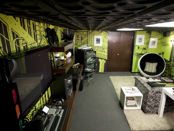 A stylish home theater room with a large TV, sound system, and graphic yellow-green wall decor
