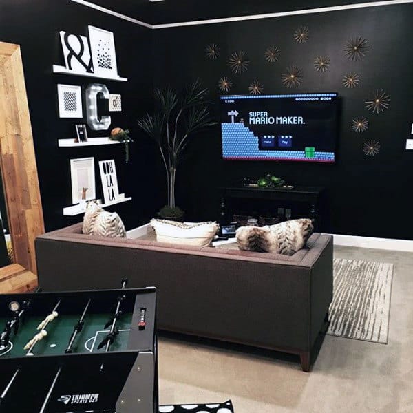 Stylish game room with a foosball table, wall art, a TV displaying Super Mario Maker, and a gray couch