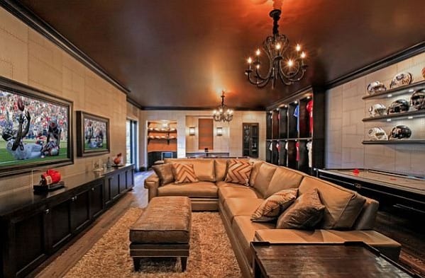 Luxurious man cave with a large sofa, sports memorabilia, a TV, and a pool table under a chandelier
