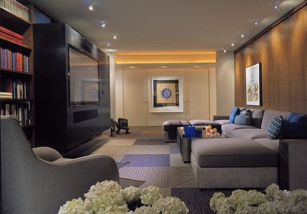 Modern living room with gray sofas, large TV, bookshelves, and a minimalist design; soft lighting enhances the ambiance