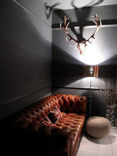 Cozy room with a brown leather sofa, antler wall decor, and a Union Jack pillow