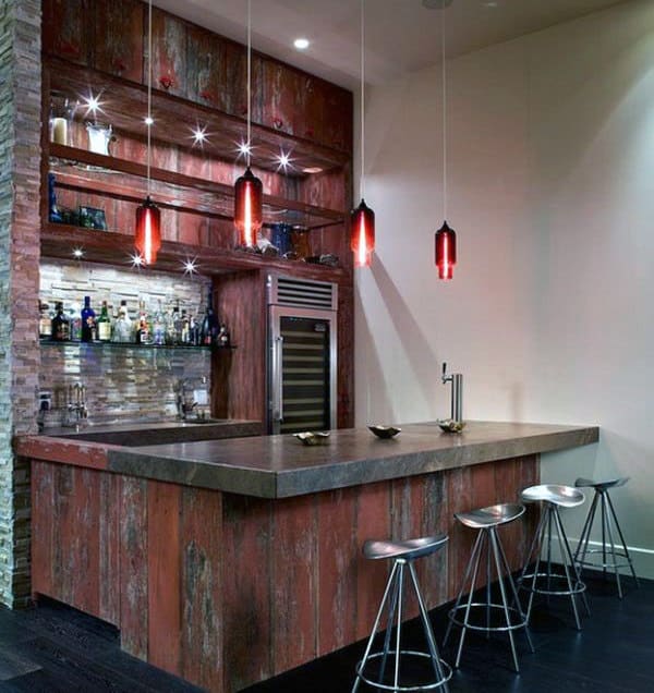 Chic bar with red pendant lights, wooden shelves, stocked bottles, a fridge, and metal stools at the counter